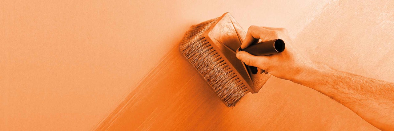 Une personne applique une brosse à lasure sur un mur