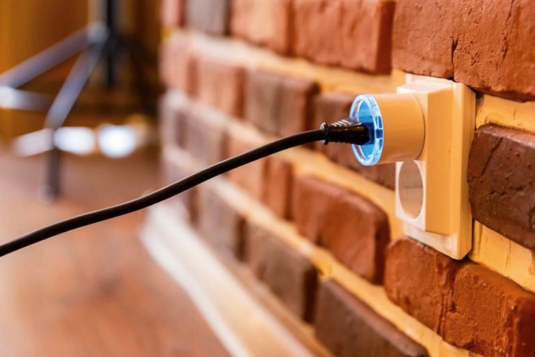 Prise de courant avec fiche branchée sur un mur en briques