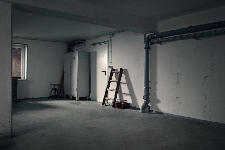 Kellerraum mit Leiter, Werkzeugkiste, Spind und Rohrleitungen.