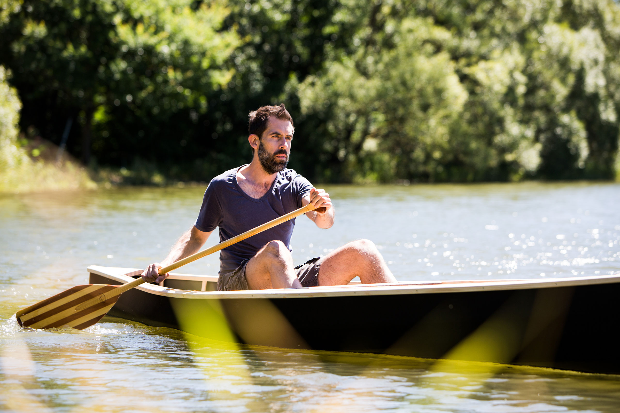 Mann rudert mit einem Paddel in einem Kanu auf einem See