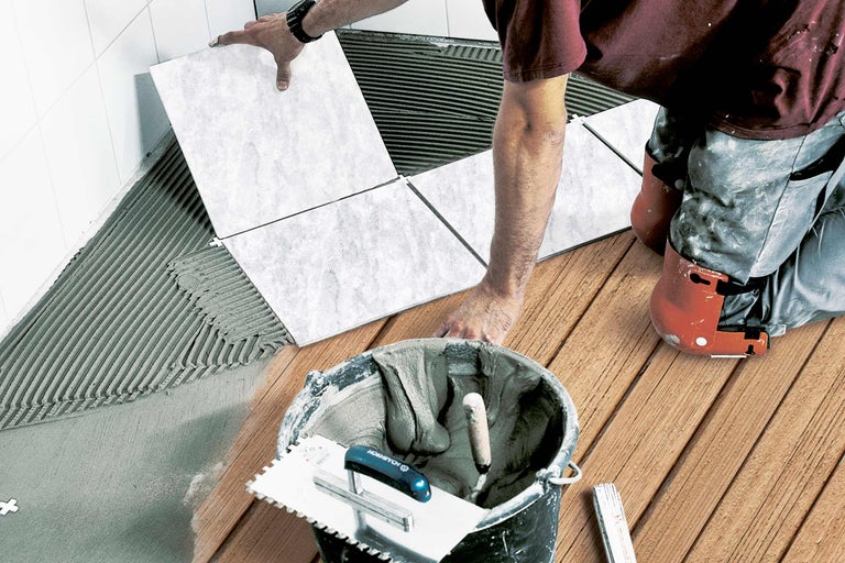 Carreleur au travail dans une salle de bains avec des outils