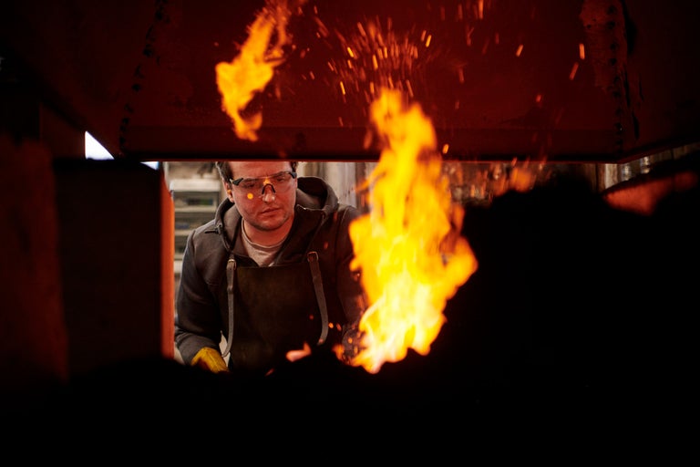 Schmied bei der Arbeit mit Flammen und Schutzkleidung
