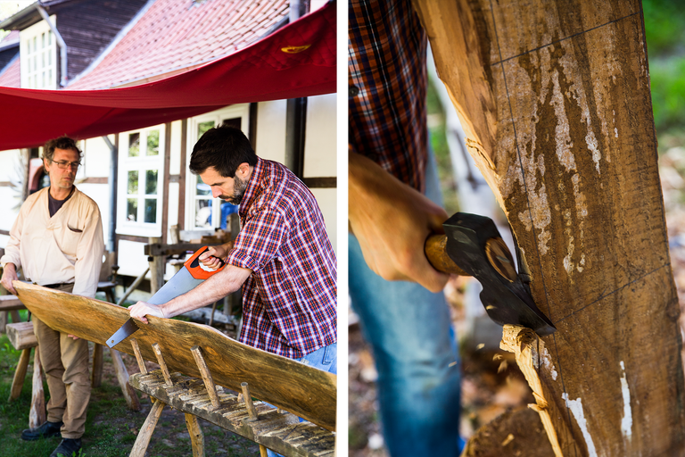 Zwei Männer bearbeiten Holz mit einer Handsäge und einer Axt.