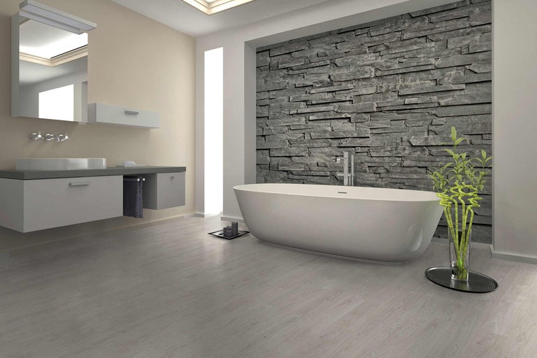 Badezimmer mit Badewanne, Waschbeckenunterschrank, Spiegel und Steinwand