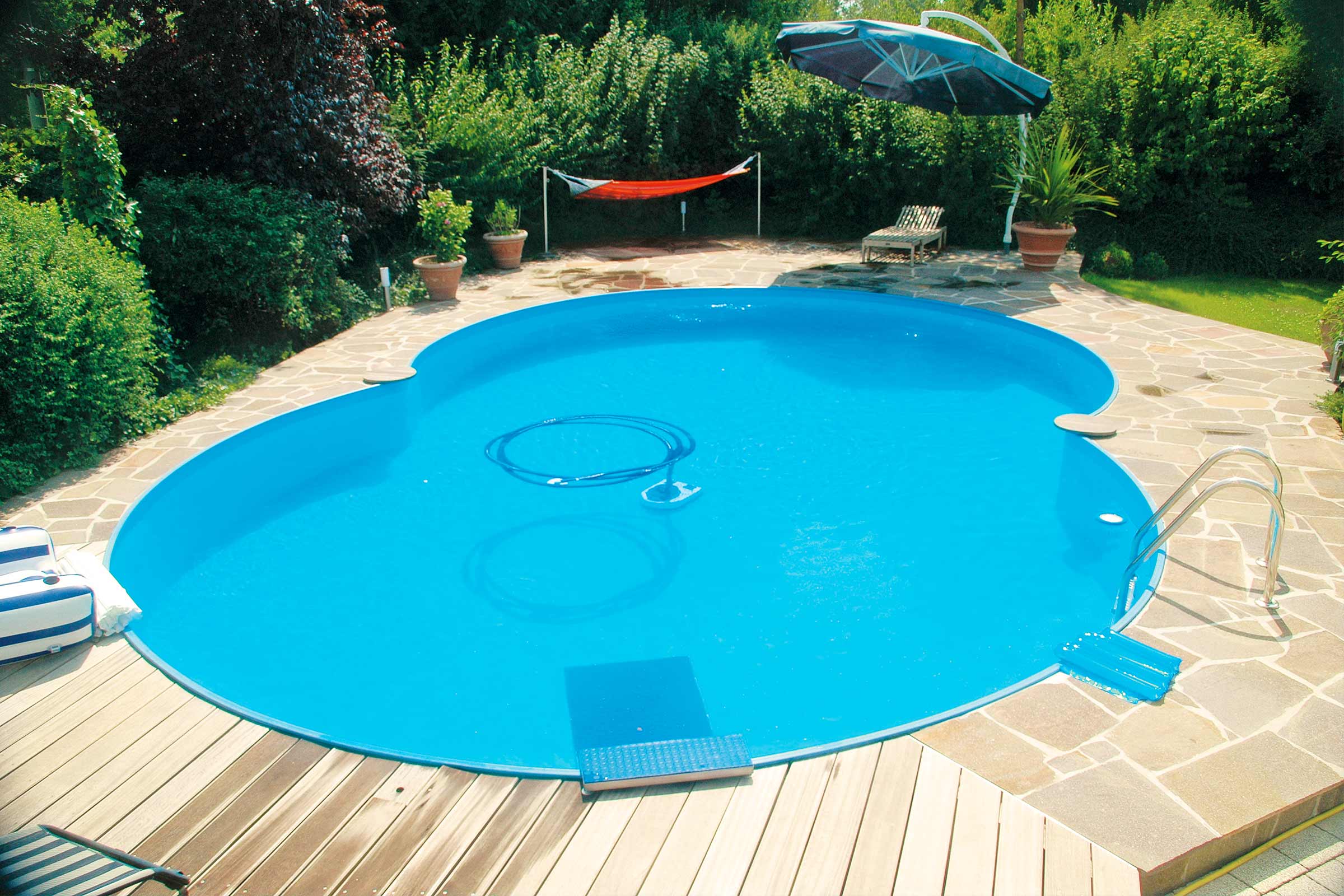 Schwimmbecken im Garten mit Leiter, Sprungbrett, Sonnenschirm und Liegestuhl