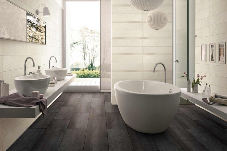 Salle de bain lumineuse avec baignoire, lavabos et carrelage de sol foncé pour un design moderne.