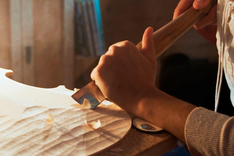 Person schnitzt mit Stecheisen Holz