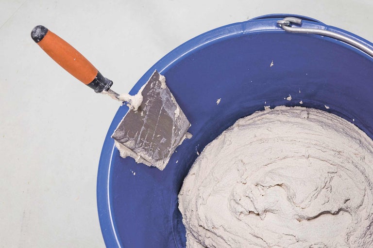 Seau de maçon rempli de mortier et d'une truelle de maçon