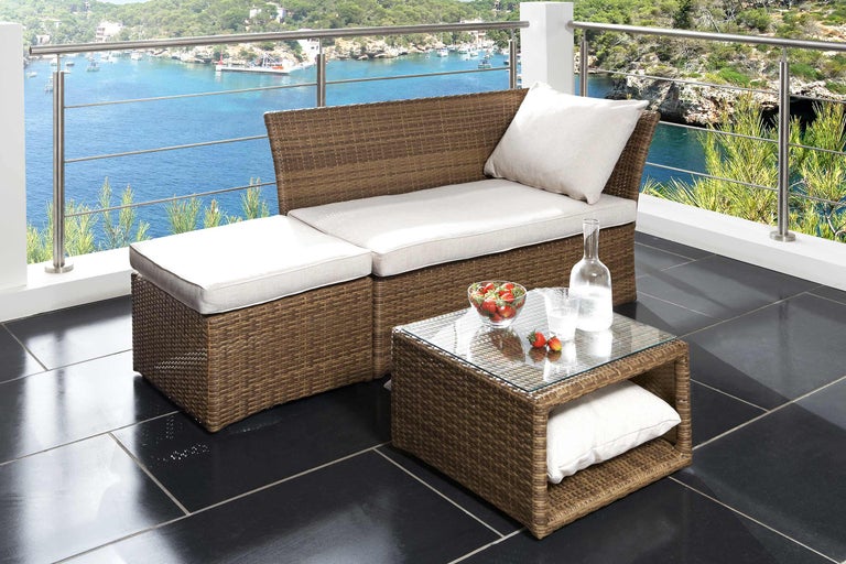Terrasse avec mobilier en rotin composé d'une banquette, d'un tabouret et d'une table avec plateau en verre