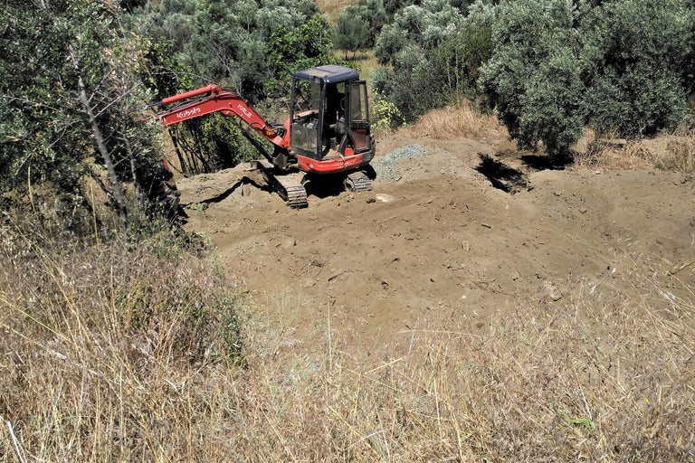 Ein roter Minibagger arbeitet im Gelände.
