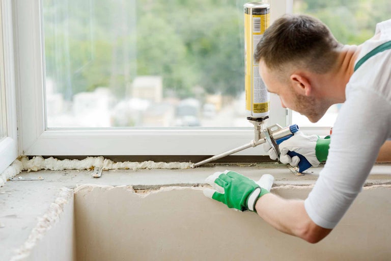 Handwerker dichtet Fenster mit Schaumpistole ab