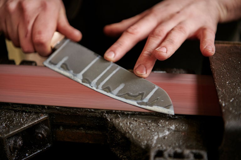 Messer wird auf einem Schleifstein geschärft