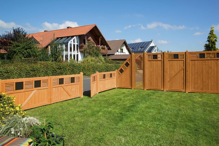 Clôture en bois avec portail dans le jardin devant des maisons