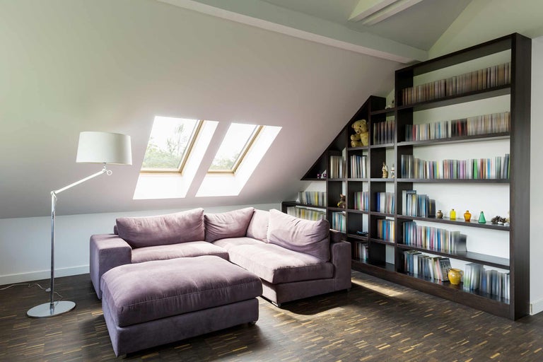Salon mansardé avec canapé d'angle, bibliothèque et fenêtres de toit