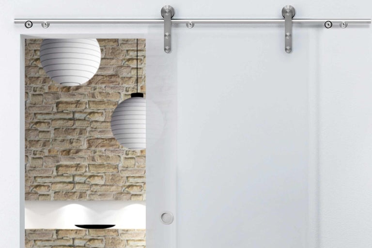 Glasschiebetür mit Edelstahlbeschlägen vor einer gemauerten Wand und Papierlampen