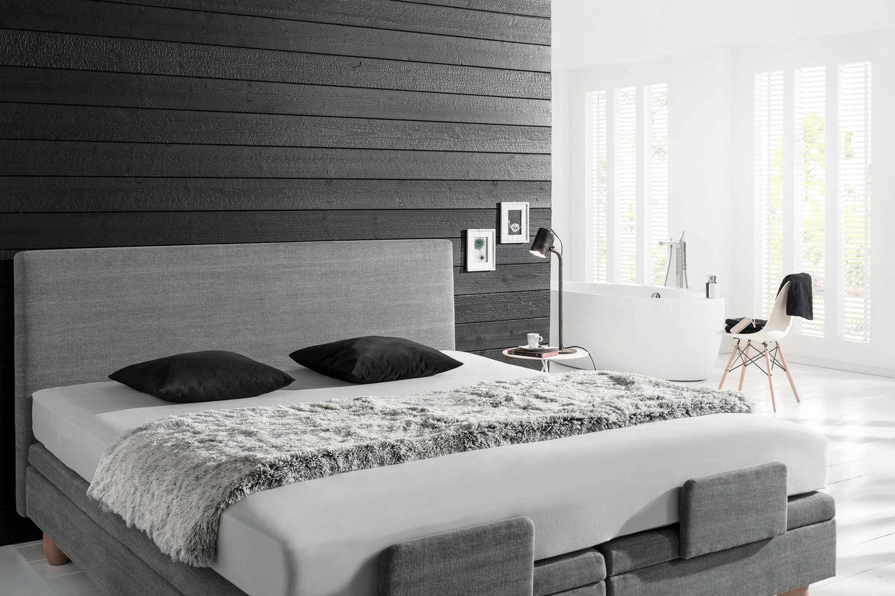 Chambre lumineuse avec lit boxspring, lampe de chevet et baignoire