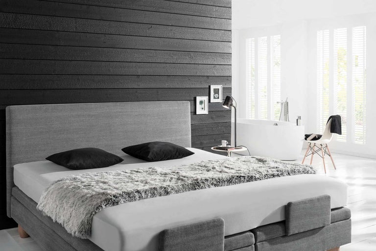 Chambre lumineuse avec lit boxspring, lampe de chevet et baignoire