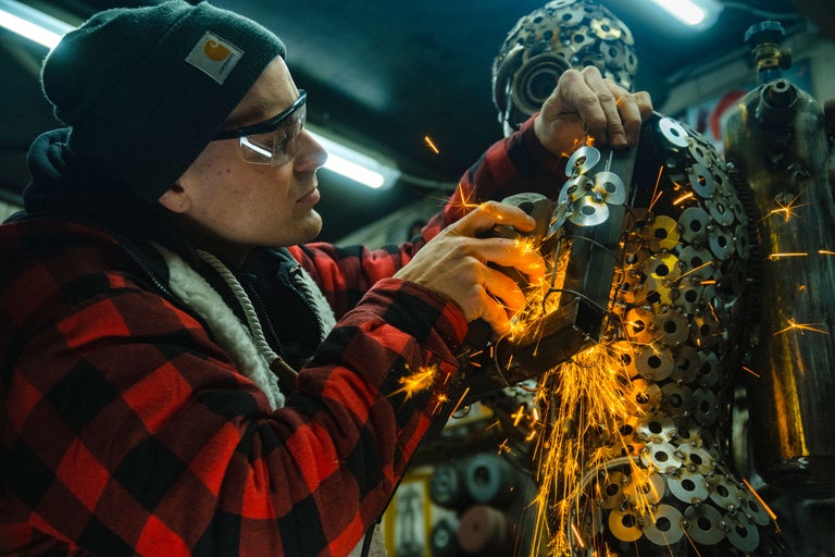Handwerker bearbeitet Metallkonstruktion mit Winkelschleifer, Funken sprühen.