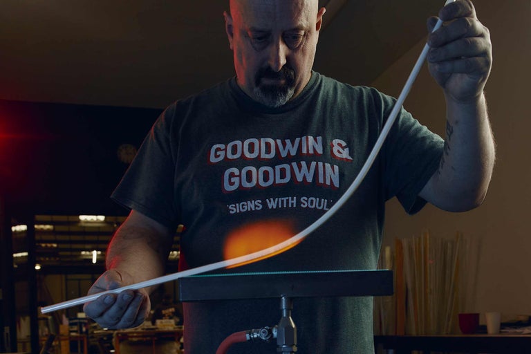 Ein Mann biegt ein Glasrohr mit einer Flamme für die Herstellung von Leuchtreklamen.