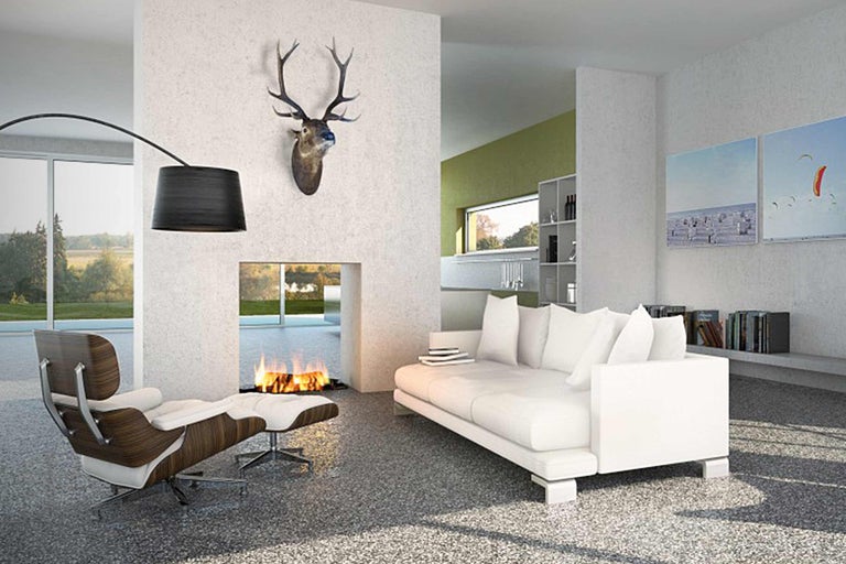 Salon lumineux avec cheminée, canapé, fauteuil et bois de cerf au mur