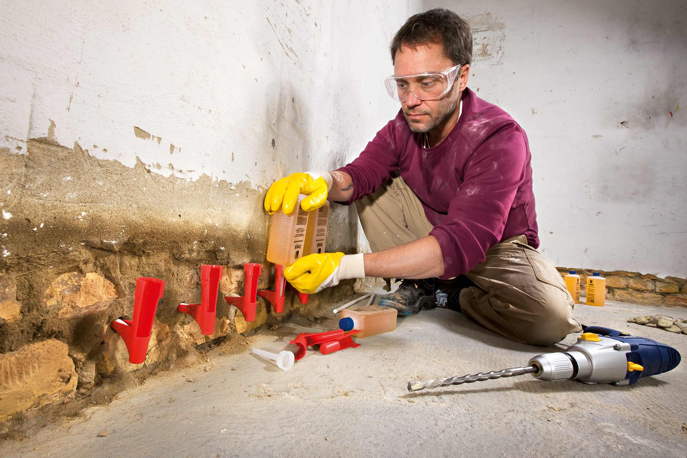 Handwerker bei der Injektion einer Horizontalsperre in eine Wand zur Sanierung von Feuchtigkeitsschäden