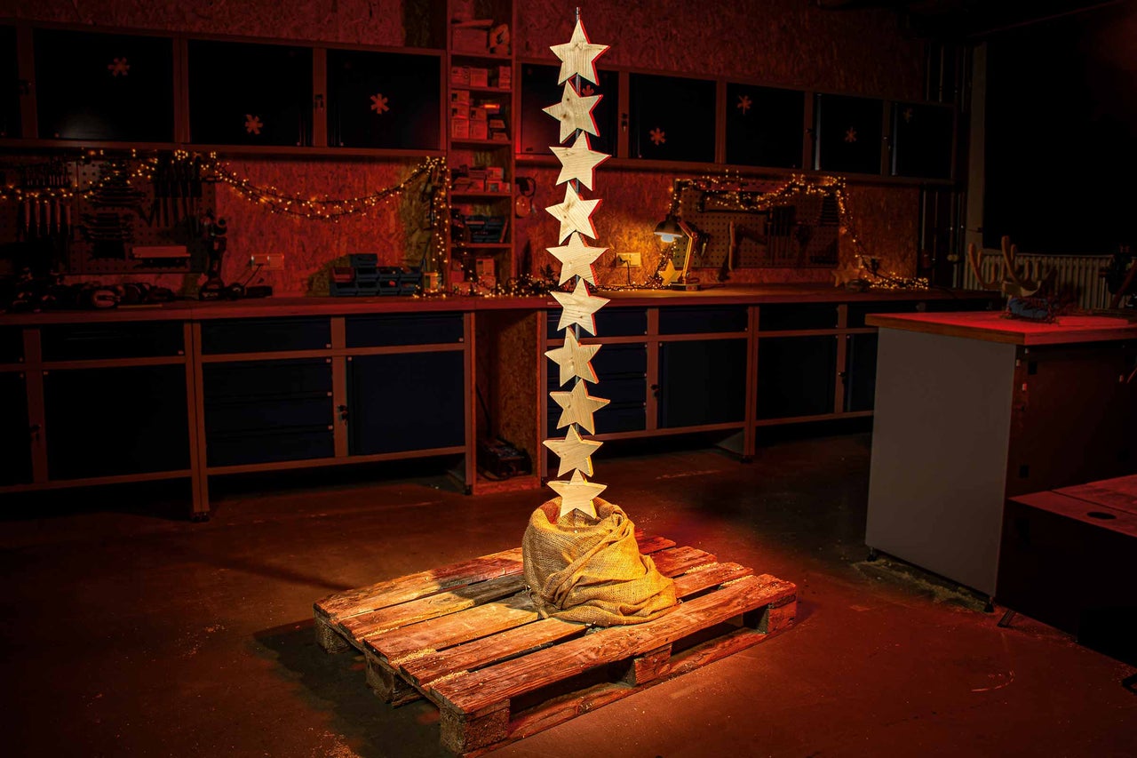 Décoration d'atelier avec des étoiles en bois sur une palette et une guirlande lumineuse en arrière-plan.