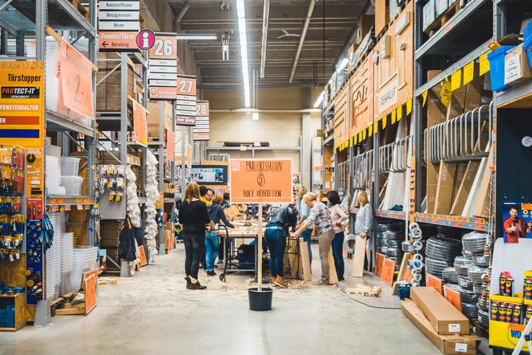 Vue intérieure d'un magasin de bricolage Hornbach avec des étagères, des marchandises et des clients à un poste de projet pour le travail du bois.