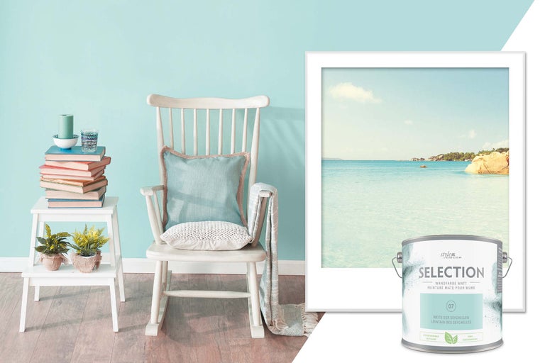 Dekorative Wohnszene mit Farbeimer, Schaukelstuhl, Wandbild und Beistelltisch