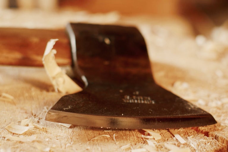 Nahaufnahme einer Axt auf einem Holzstück mit Holzspänen