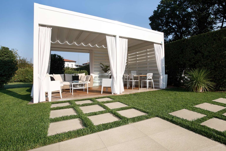 Pavillon de jardin avec mobilier de terrasse et chemin de dalles en pierre dans le jardin