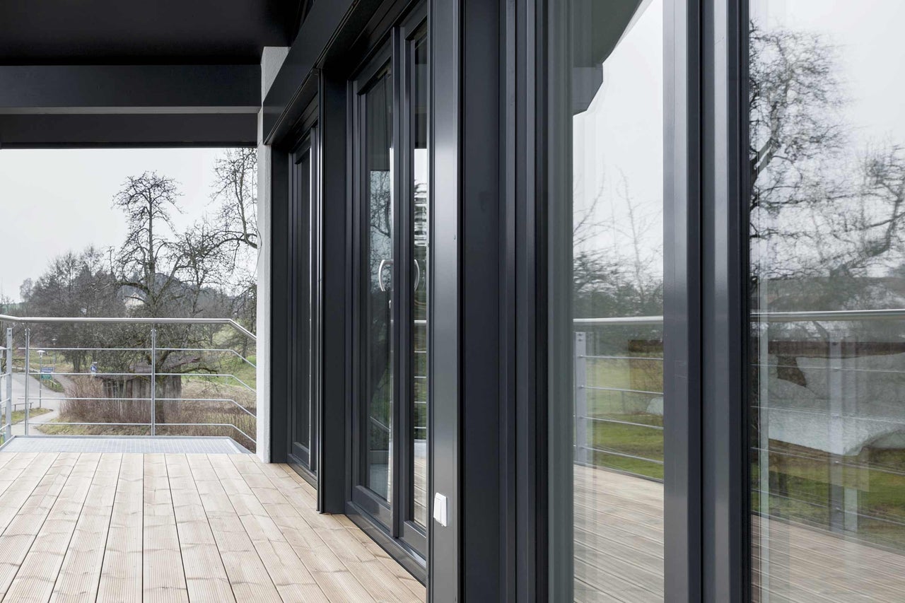 Mehrteilige Schiebetüranlage aus Glas und Aluminium auf einer Terrasse mit Holzboden