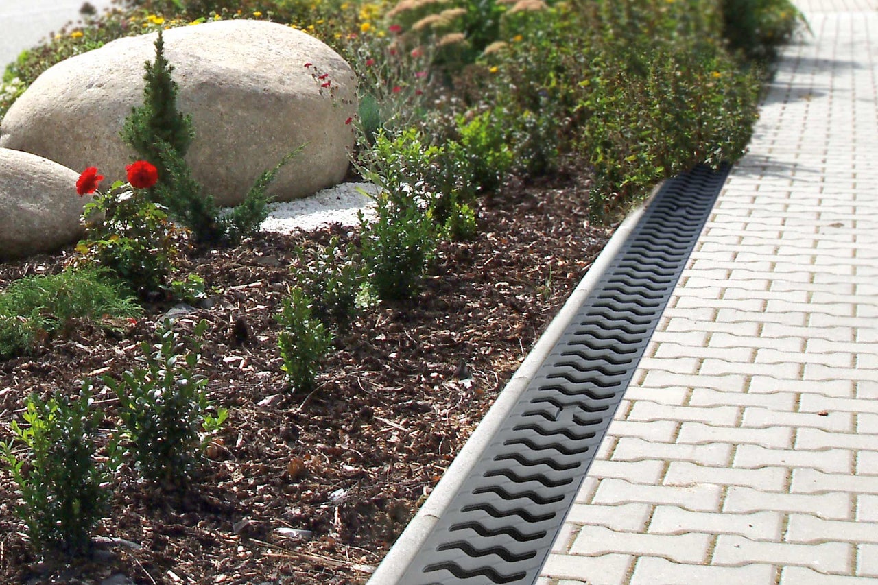 Aménagement paysager avec caniveau de drainage à côté de pavés de trottoir
