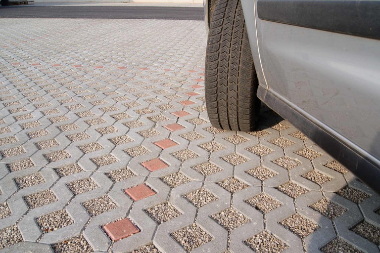 Verbundpflastersteine mit Kiesfüllung neben einem Auto