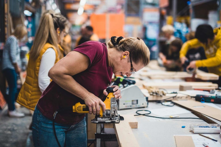 Femme utilisant une scie sauteuse pour couper du bois dans un atelier