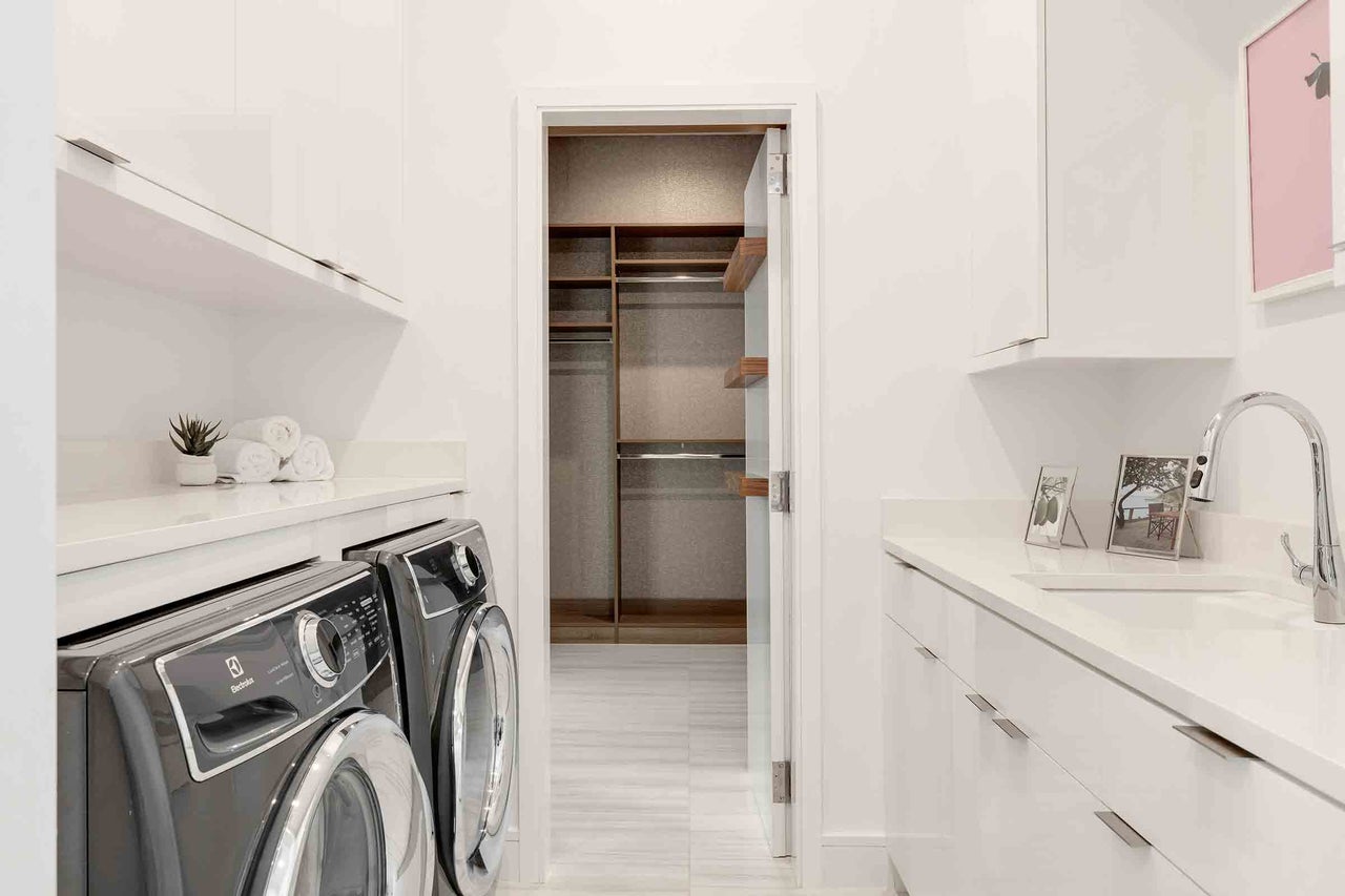 Buanderie lumineuse avec lave-linge, sèche-linge, espace de rangement, lavabo et dressing