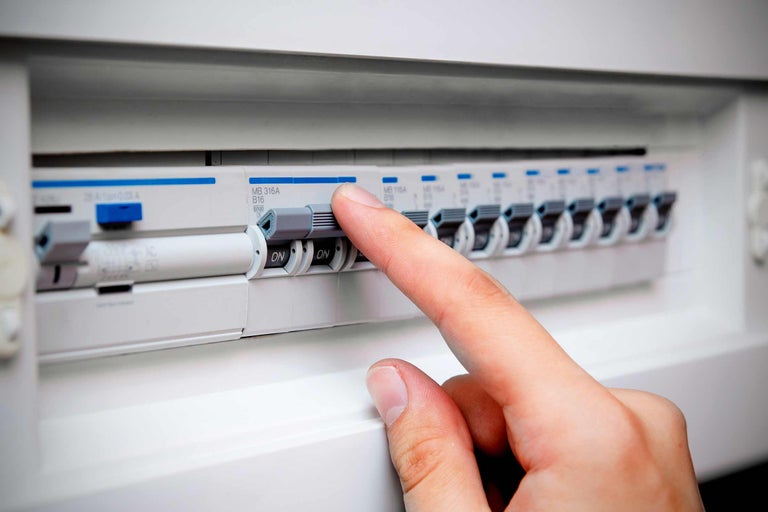 Ein Sicherungskasten mit einer Hand, die einen Schutzschalter betätigt