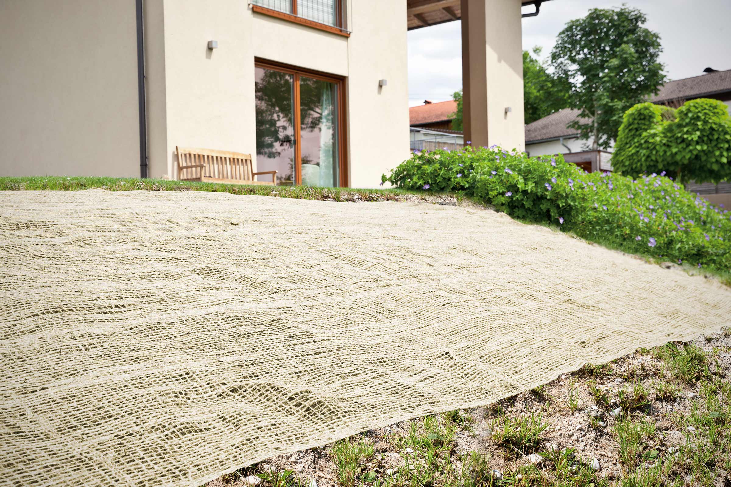 Bodenabdeckung aus Jute auf einer Grünfläche vor einem Haus