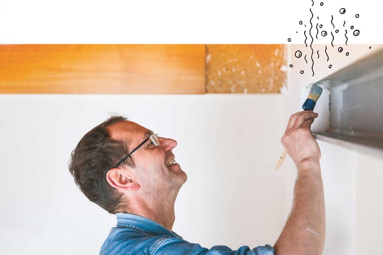 Un homme peint un angle avec un pinceau.