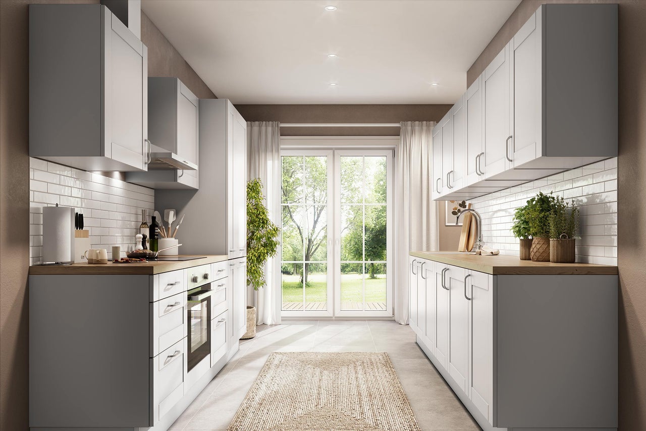 Cuisine moderne en deux rangées, façades blanches à cadre, plans de travail en bois et crédence blanche. Lumineuse avec vue sur le jardin.