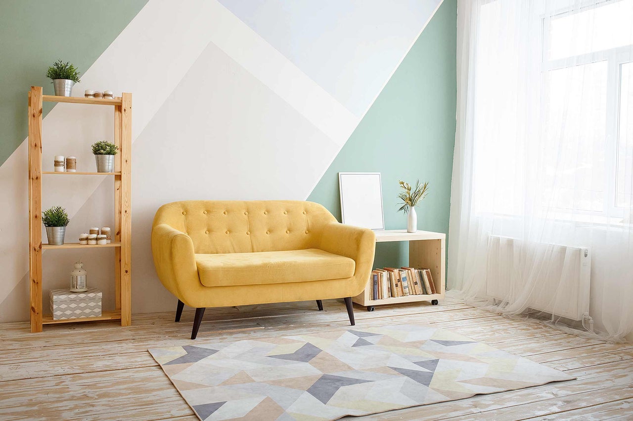 Salon lumineux avec canapé jaune, étagère en bois et tapis géométrique