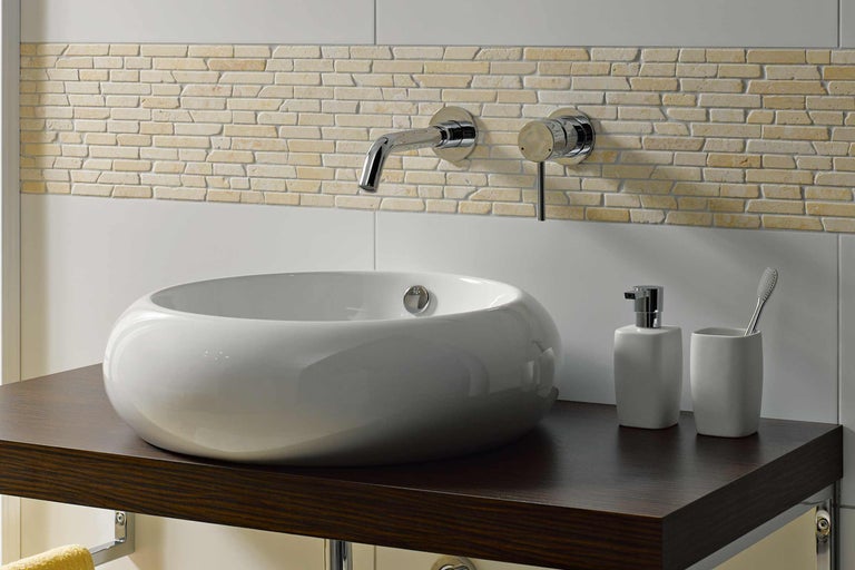 Salle de bains moderne avec vasque à poser, robinetterie et carrelage mural aspect pierre