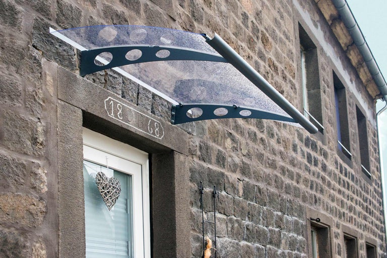 Auvent en polycarbonate sur un mur de maison en pierre