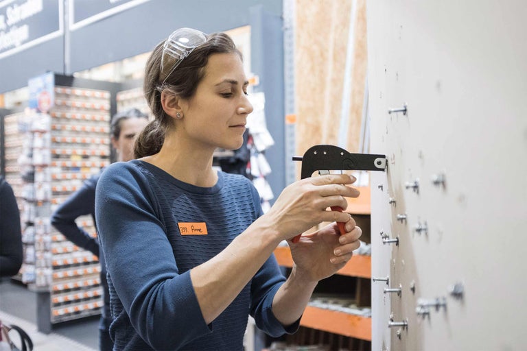 Une femme portant des lunettes de protection utilise une pince à riveter pour fixer un rivet.