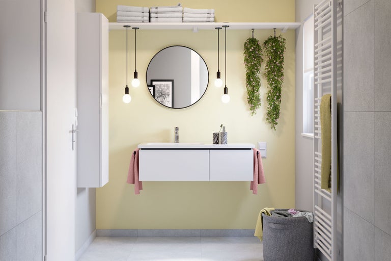 Salle de bains moderne avec lavabo, miroir, serviettes, radiateur et éléments décoratifs pour une ambiance lumineuse et conviviale.