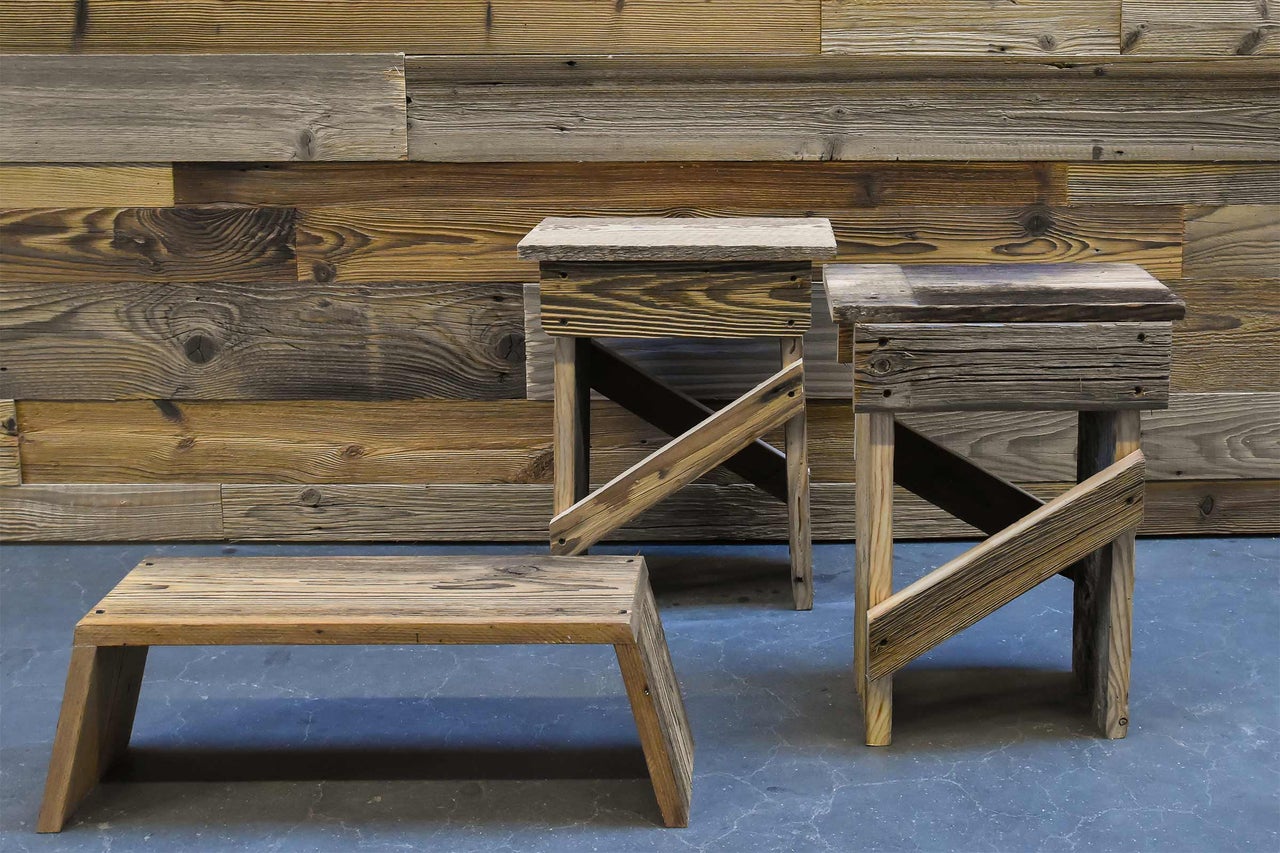 Trois tabourets en bois devant un mur en bois