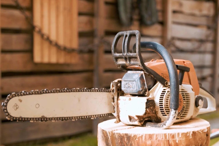 Motorsäge auf einem Holzstumpf vor einer Holzwand