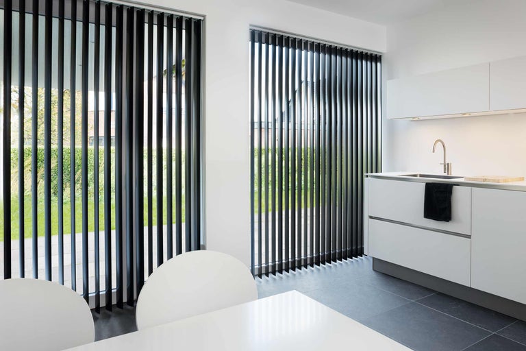 Intérieur moderne avec stores verticaux de fenêtre, table de cuisine et évier