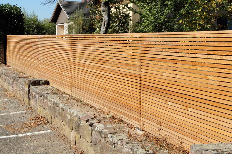 Clôture en bois avec des lamelles horizontales et un mur de pierre