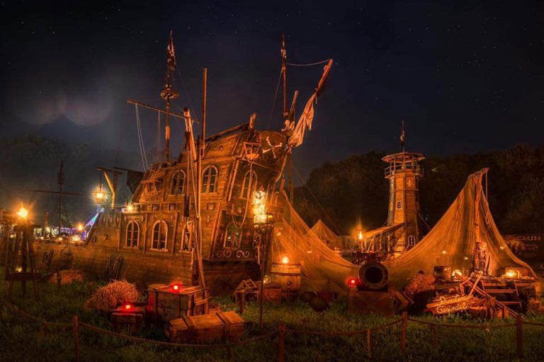 Beleuchtetes Piratenschiff mit Turm und Zelten bei Nacht