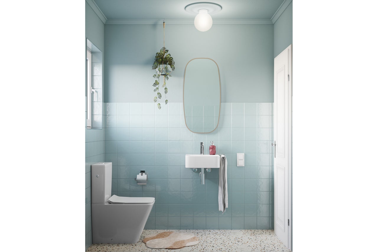 Toilettes invités modernes avec carrelage mural bleu clair, sol terrazzo, lave-mains blanc, WC au sol et un grand miroir ovale.